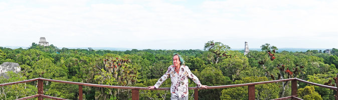 Patrick Blanc at the top of the observatory overhanging the ruins, the branches of emergent trees covered by the grey Tillandsia usneoides and the bright red leaved Tillandsia juncea, Tikal, Peten, Guatemala, Jan. 2020