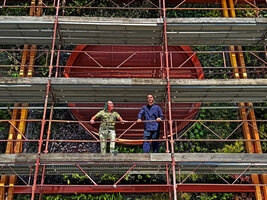 Patrick Blanc and Bob Morard on the scaffolding just below a circular aeration structure at the end of plant installation of the Vertical Garden of the new Oiken electric substation, Sion, Switzerland, June 2026