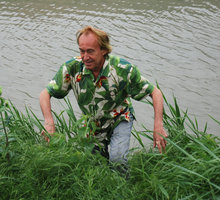 Patrick Blanc climbing among grasses on a river bank, Italy May 2010