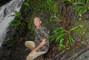 Patrick Blanc leaning against a vertical seeping rock covered by a flowering population of a tiny new Dicranopygium species with entire adult leaves,Terco, Nuqui, Choco, Colombia, Nov. 2016