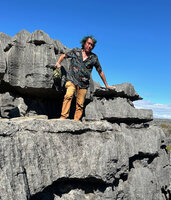 Patrick Blanc leaning over a narrow ledge to observe the plants fixed in karst anfractuosities, Ankarana Tsingy NP, Madagascar, Aug. 2024